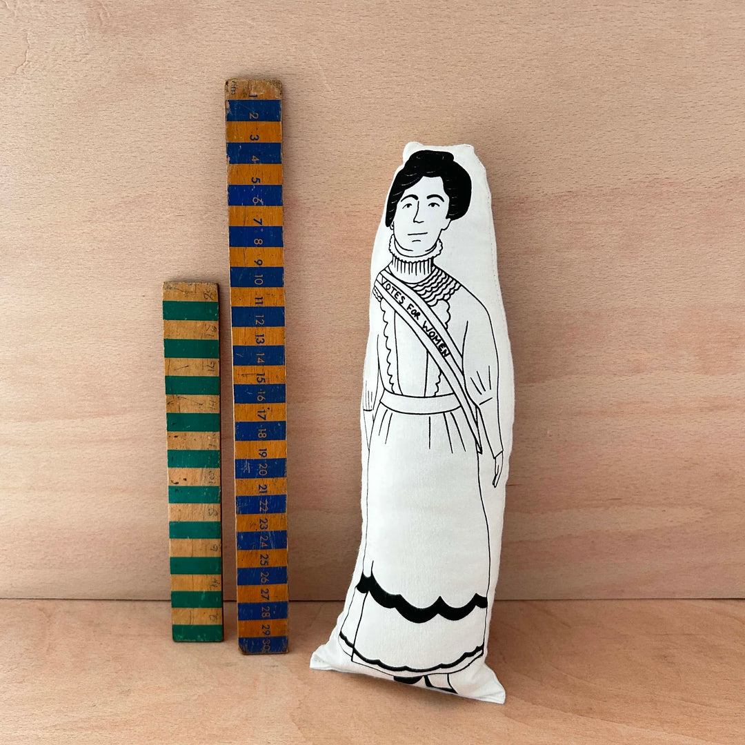 Screen printed doll cushion of Emmeline Pankhurst next to two wooden rulers against a wooden background