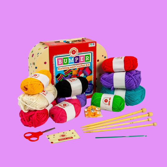 Knitting and crochet kit with colorful yarn, needles, and scissors on a white background