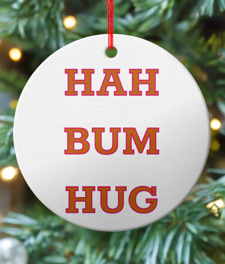 Round white ornament with red text 'HAH BUM HUG' hanging on a Christmas tree.