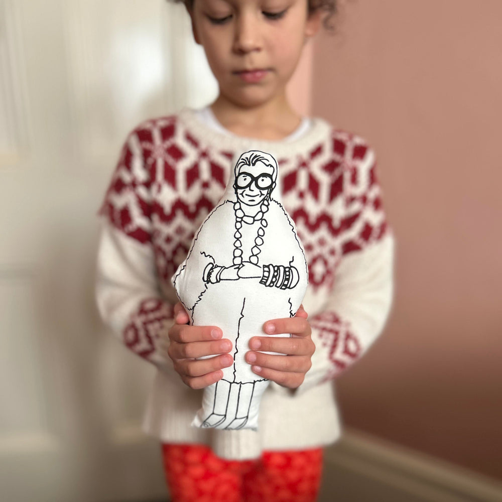A child holding screen printed doll cushion of fashion designer Iris Apfel
