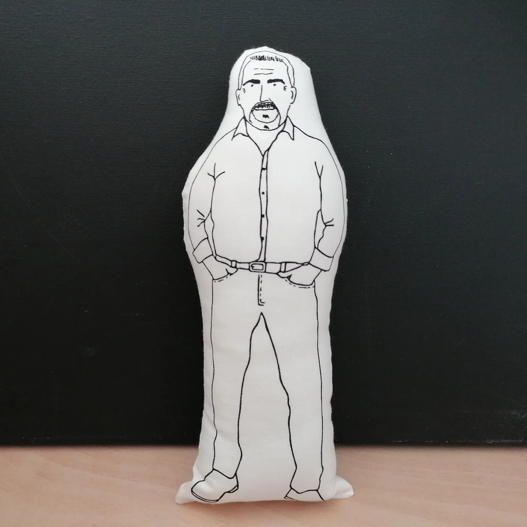 Screen printed doll cushion with white fabric and black illustration depicting TV presenter and baker Paul Hollywood wearing a shirt and jeans with his hands in his pockets