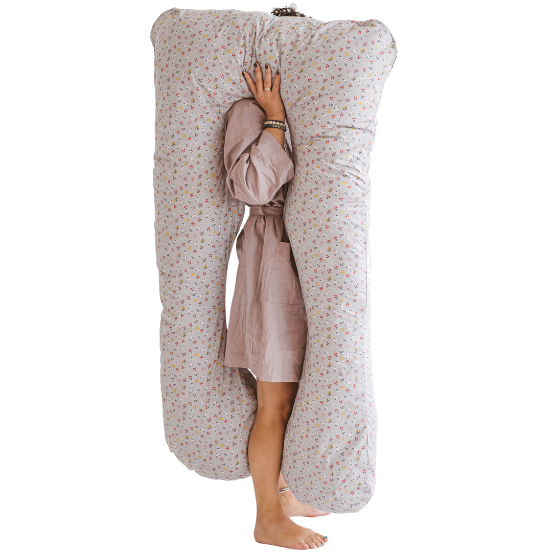 Person standing holding the U-shaped pillow on their shoulder, showing its full length which reaches to their ankles