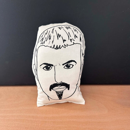 Screen printed doll cushion depicting singer songwriter George Michael's face, with a goatie beard