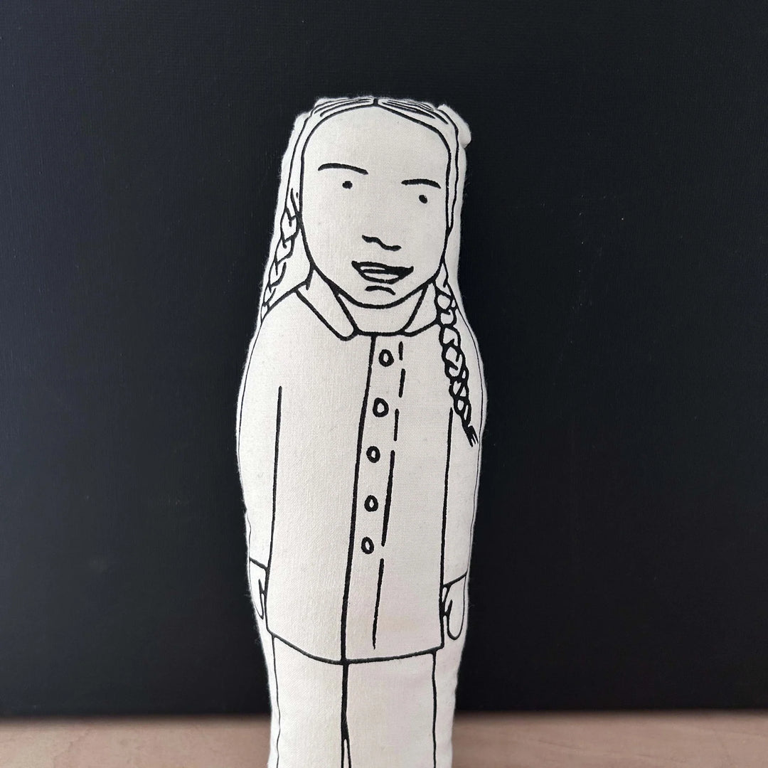 Screen printed doll cushion with white fabric and black illustration depicting a cartoon image of climate activist Great Thunberg