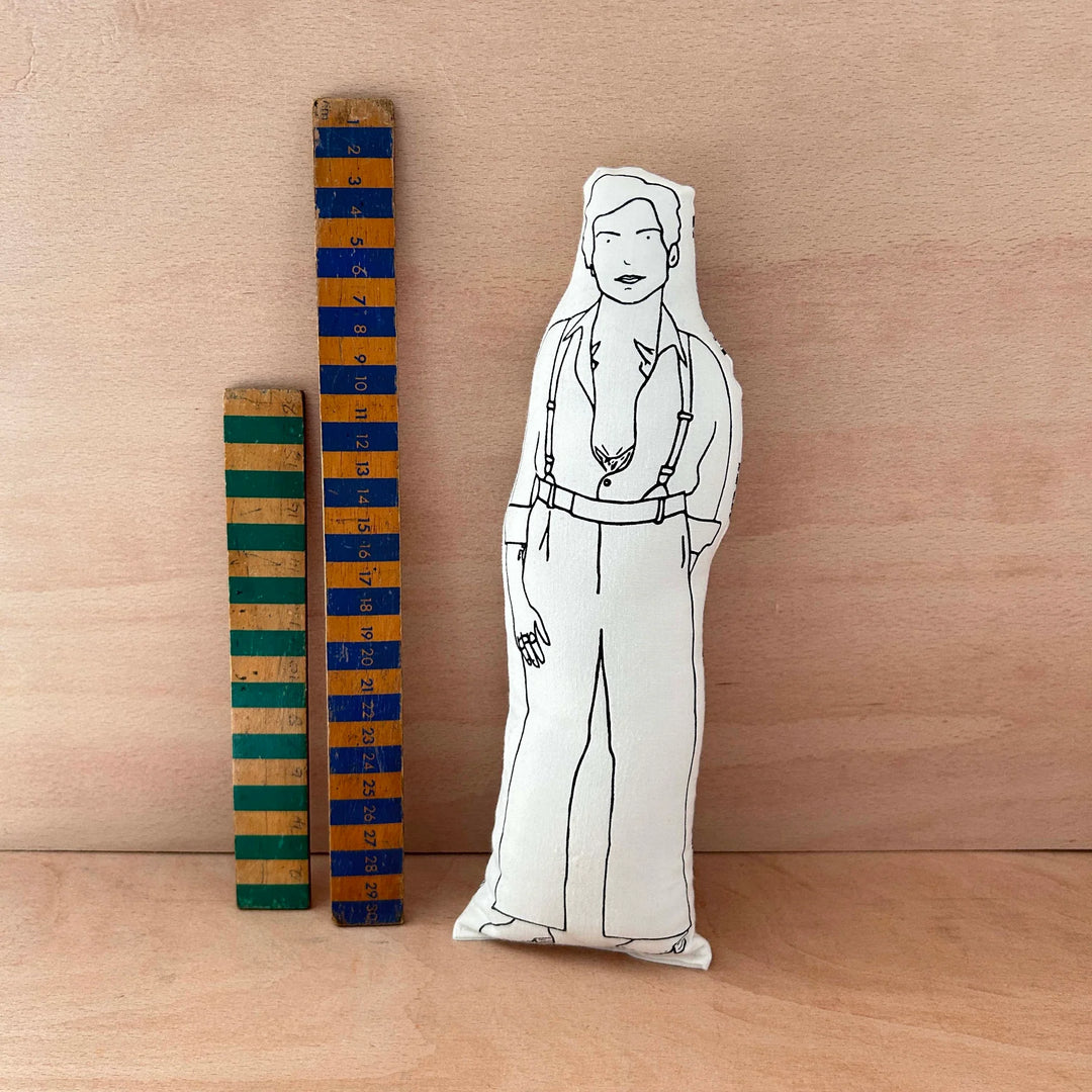 Screen printed doll cushion of Harry 
Styles next to two wooden rulers on a wooden background