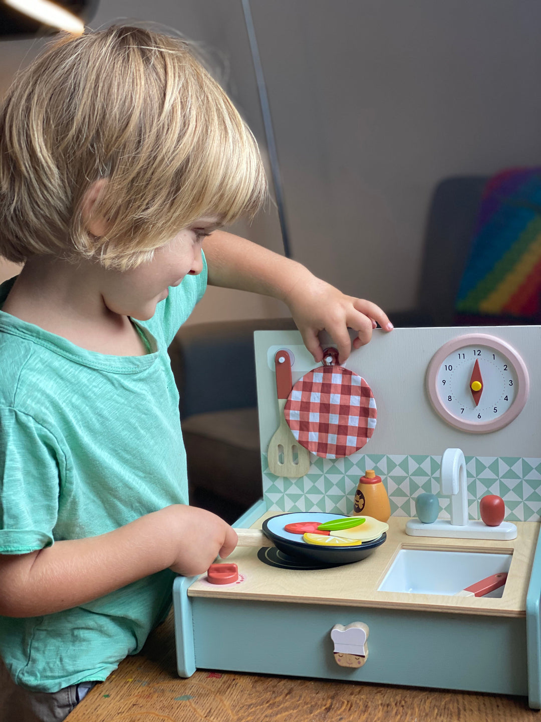 Child playing with a wooden toy kitchen set