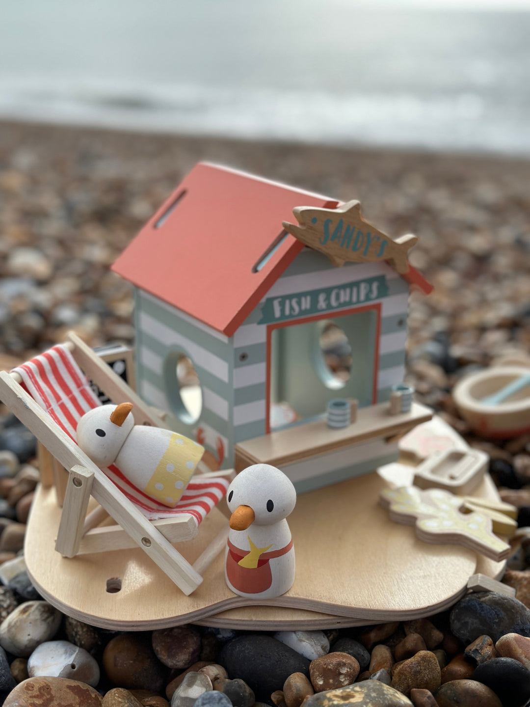 Miniature toy fish and chip shop with two ducks on a pebble beach