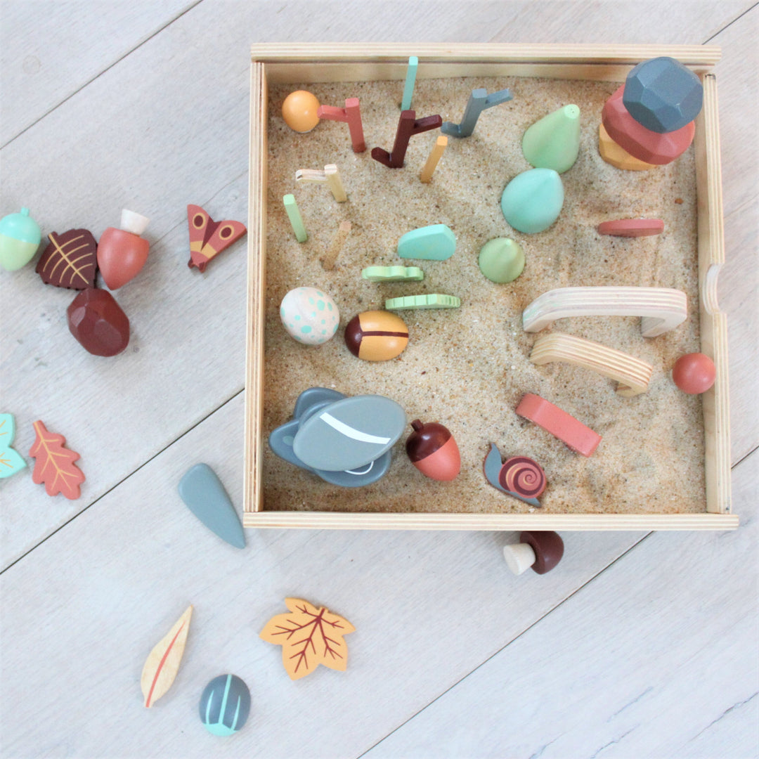 Colorful wooden toys in a box on a light grey floor
