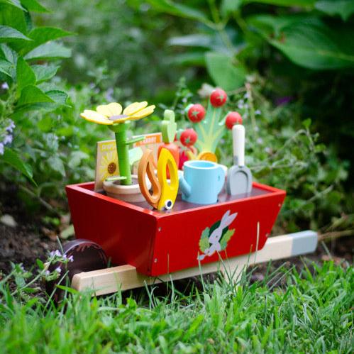 Colourful toy garden set with tools and plants on a grassy background