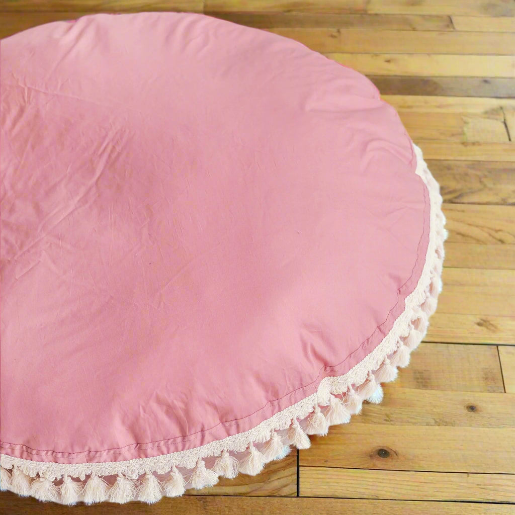 Close up of round pink cushion with white tassels