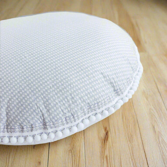 Close up of floor cushion showing the delicate diamon pattern and the pom pom edge