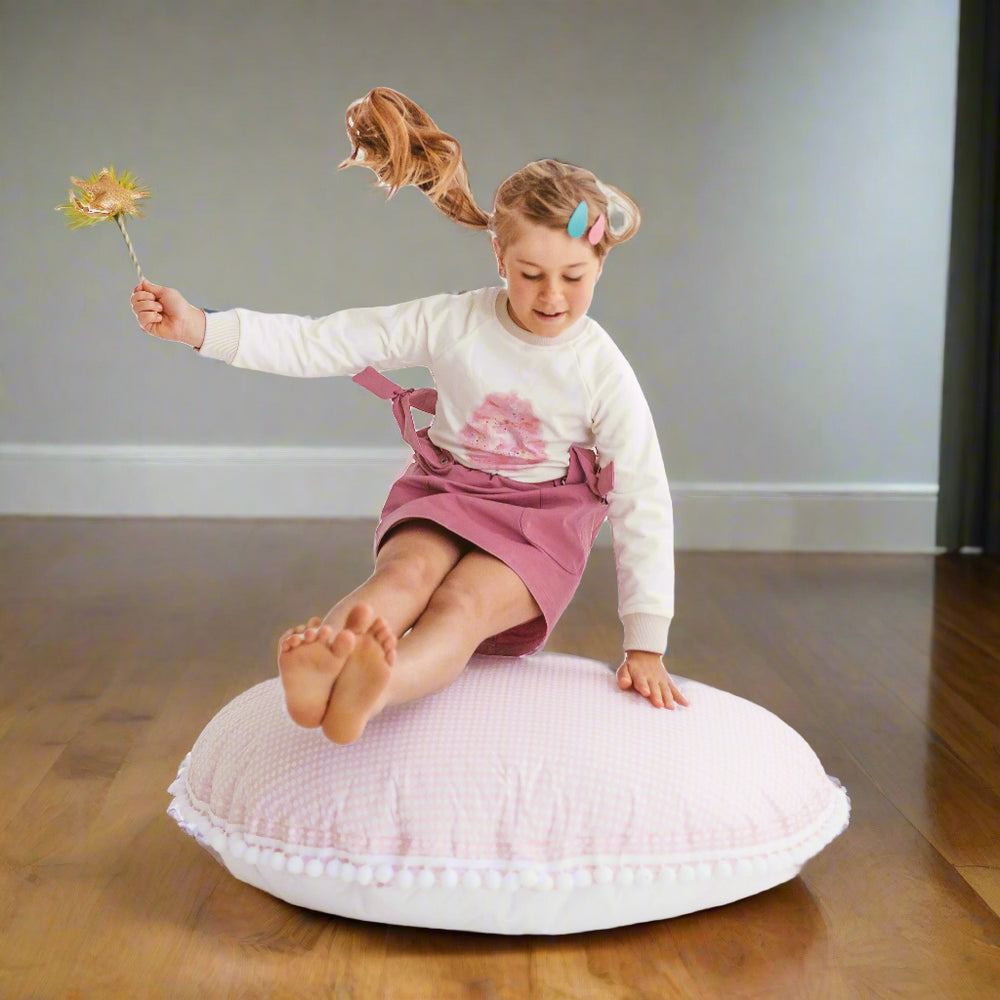 Child jumping onto pale pink floor cushion