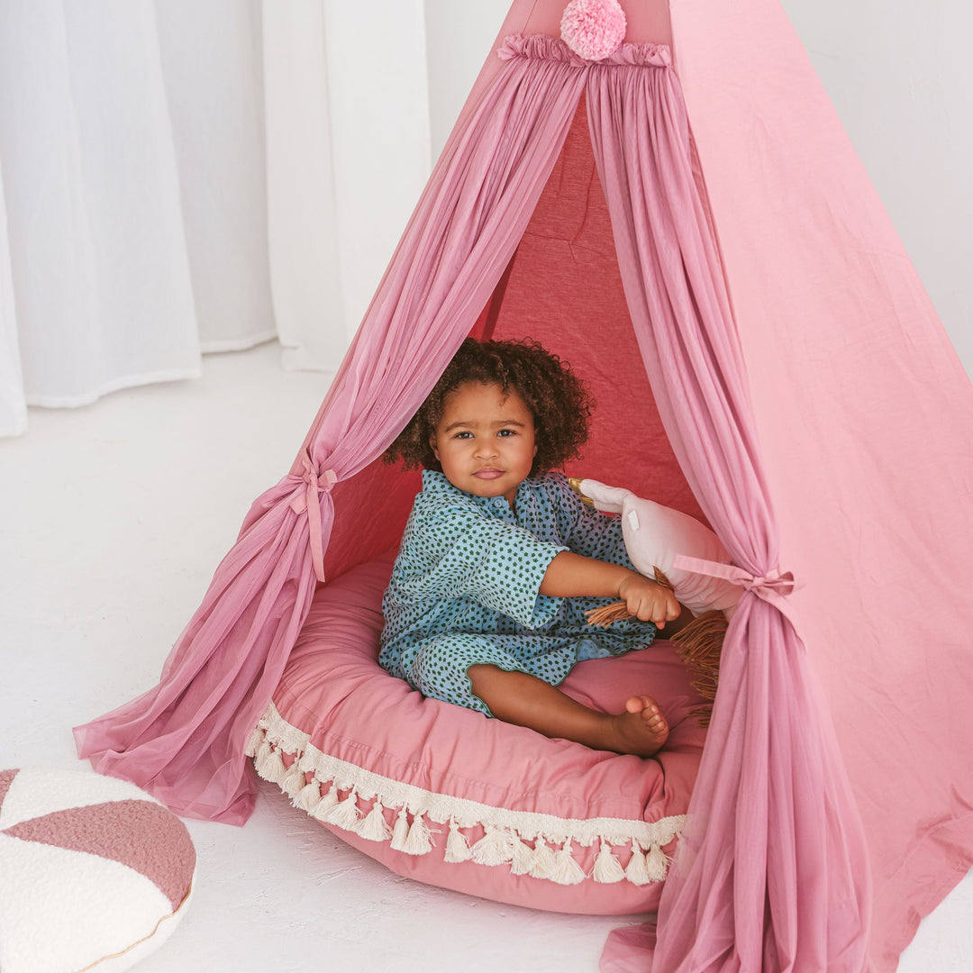 Child sitting inside a pink play tent with a matching pink floor cushion