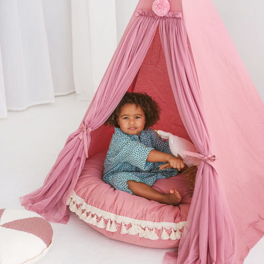 Child sitting inside a pink play tent with a matching pink floor cushion