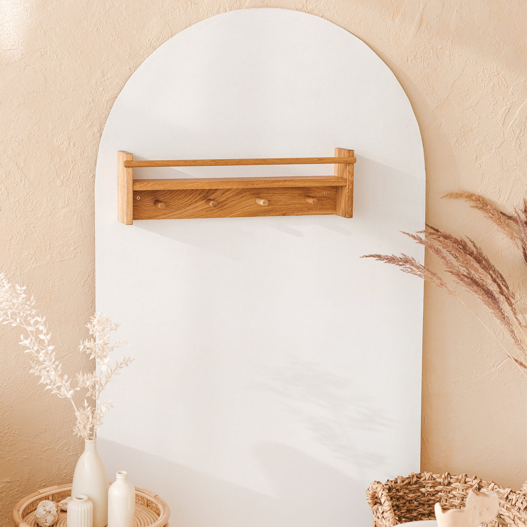 Wooden shelf mounted on a white wall with decorative elements like candles and plants.
