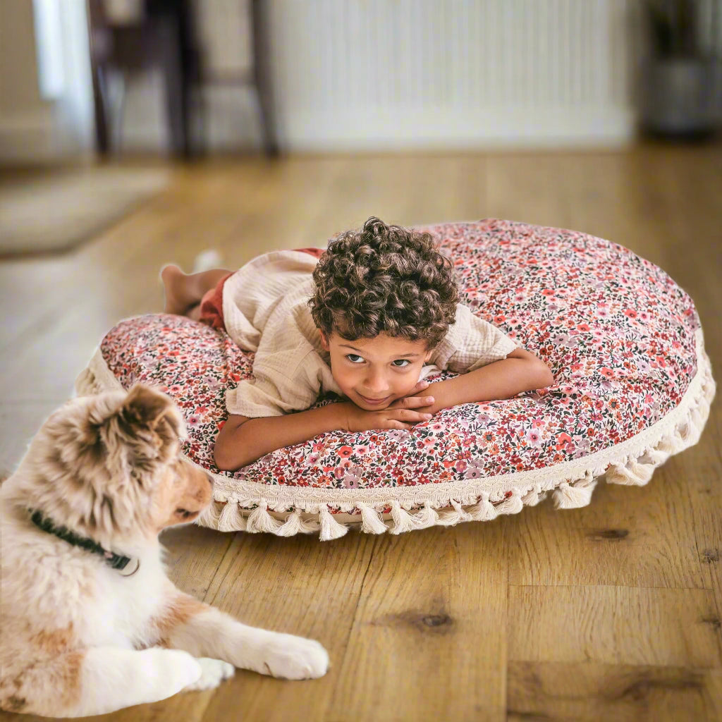 Child lying on a floral cushion with a dog next to him