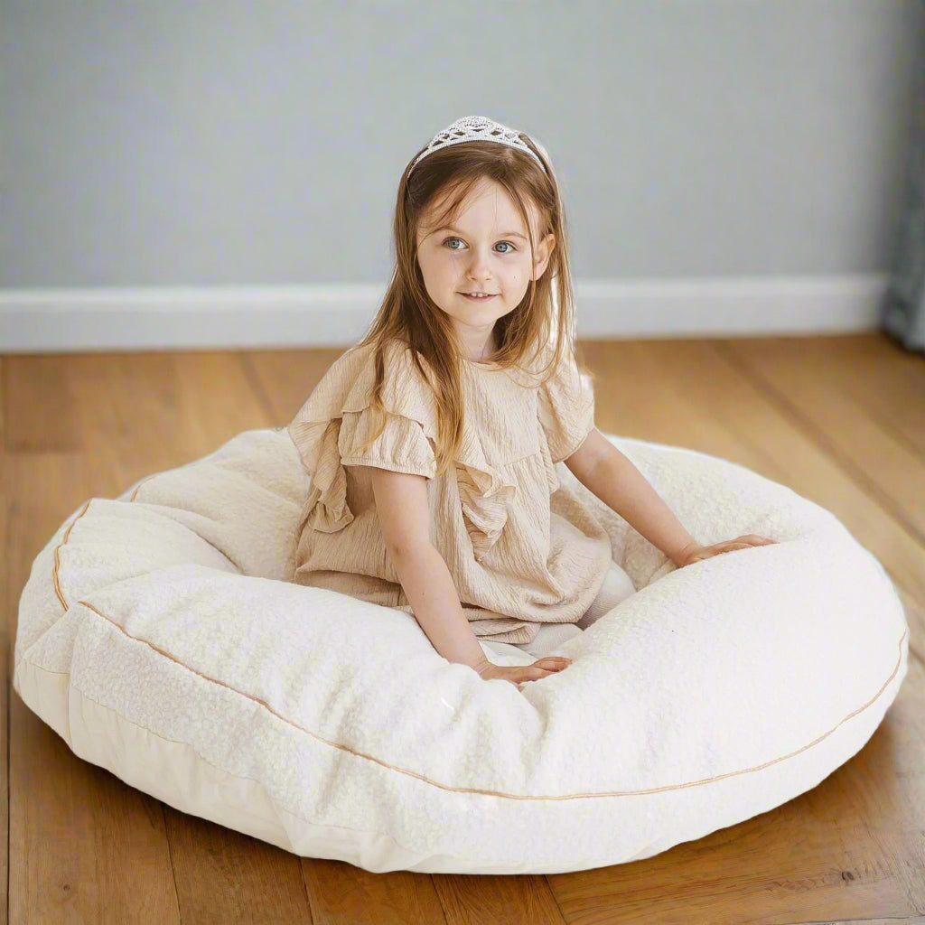 Young girl sitting on a large pale beige floor cushion