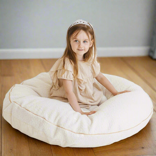 Young girl sitting on a large pale beige floor cushion