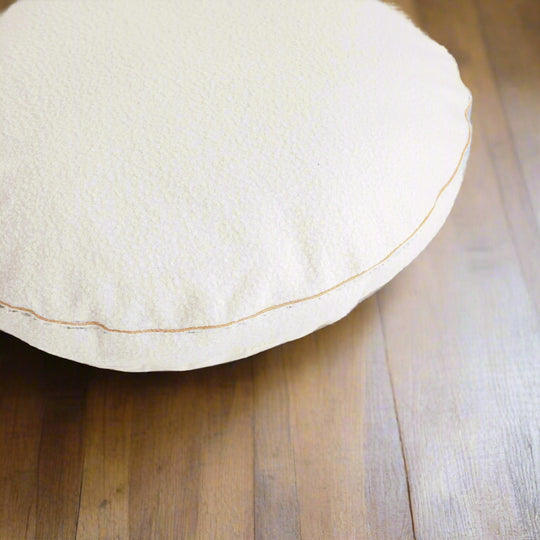 Close-up of a circular pale beige floor cushion with a gold trim