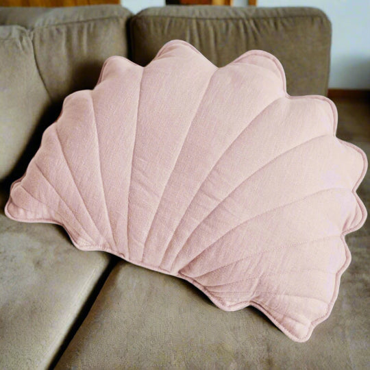 Pink shell-shaped cushion on a sofa