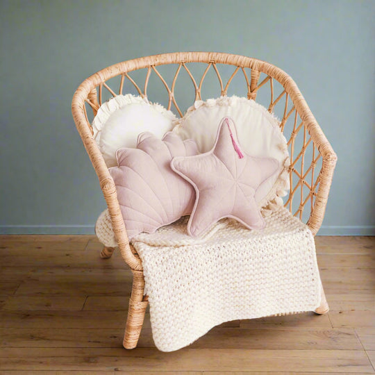 Wicker chair with pink star-shaped cushions and a white blanket in a living room setting