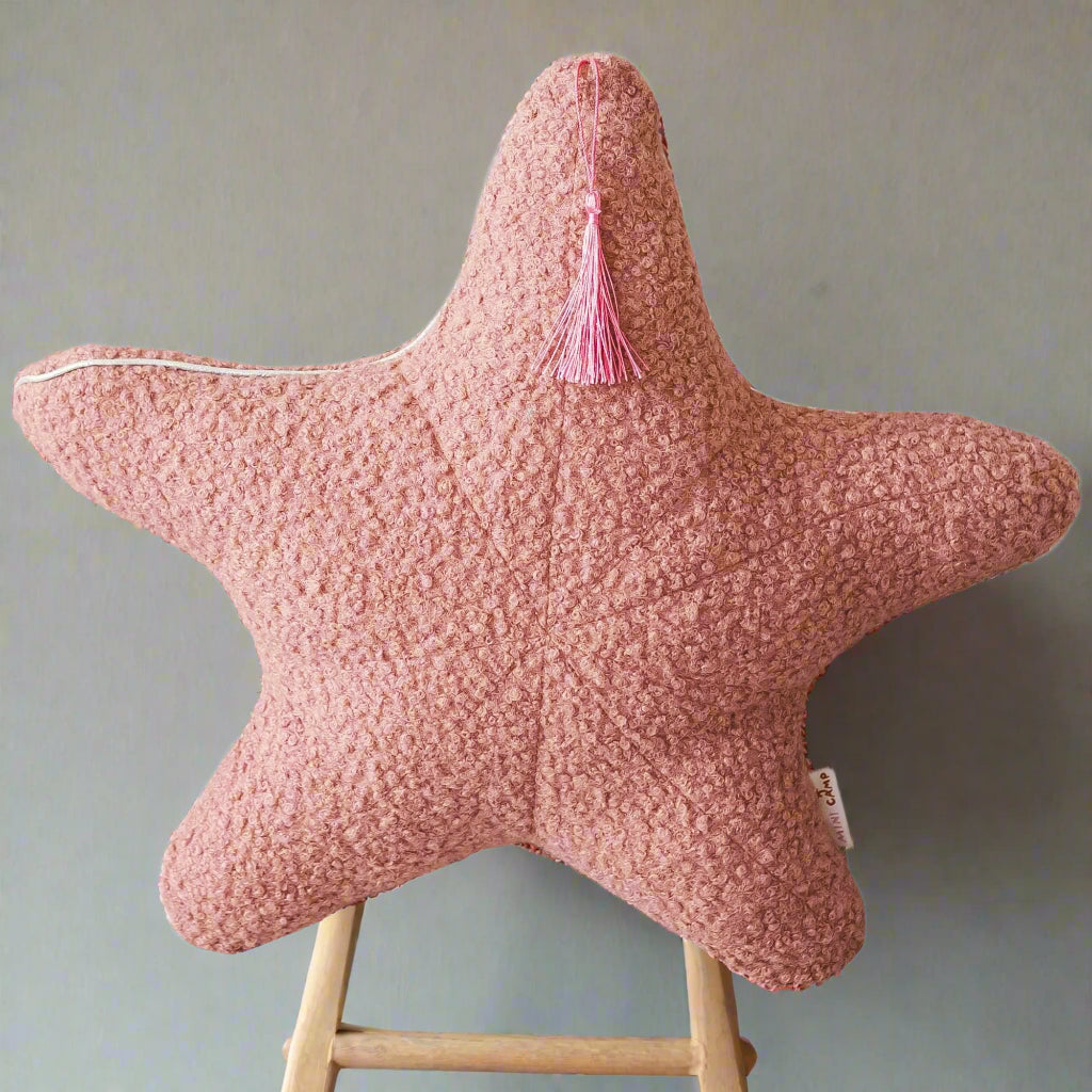 Pink star-shaped pillow with a tassel on a white background