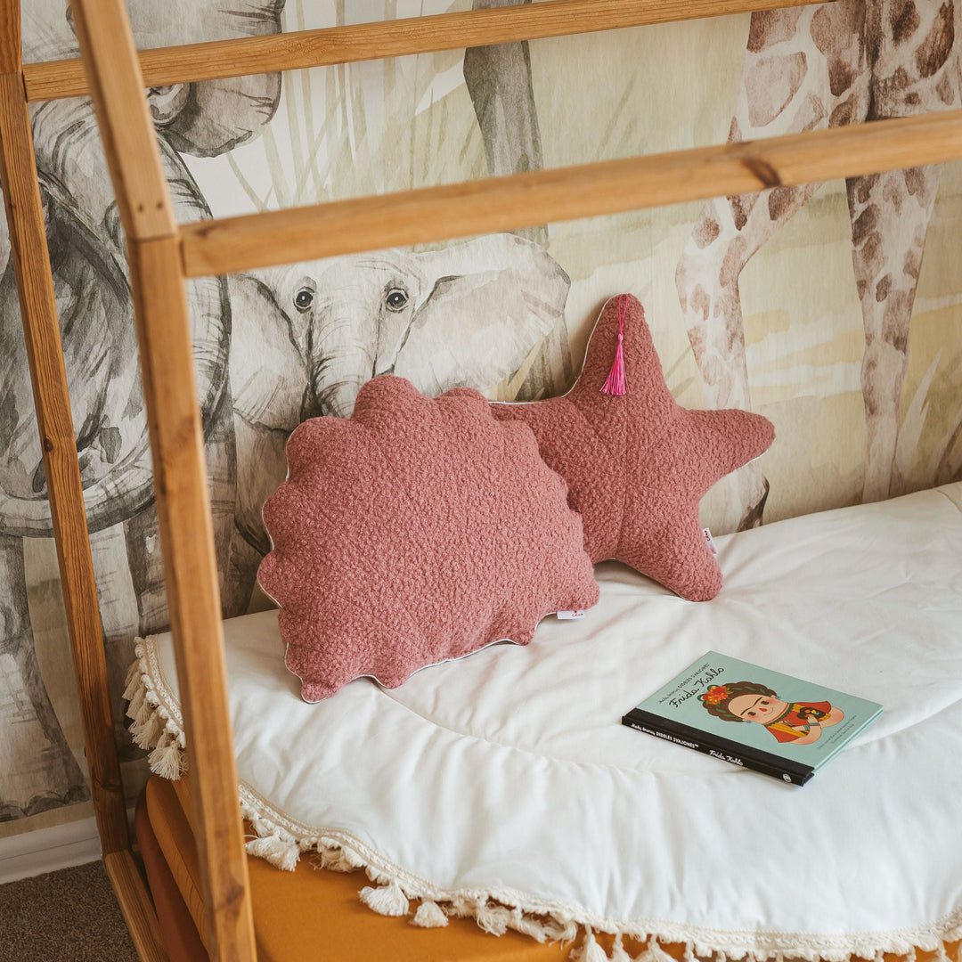 Pink textured pillows on a bed with animal-themed wallpaper