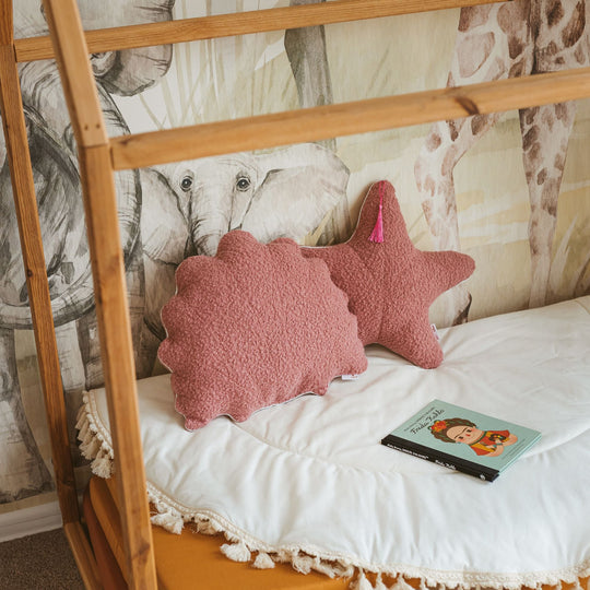 Pink textured pillows on a bed with animal-themed wallpaper