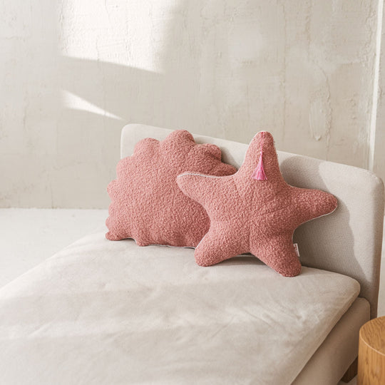 Pink starfish-shaped cushions on a white sofa with a neutral background