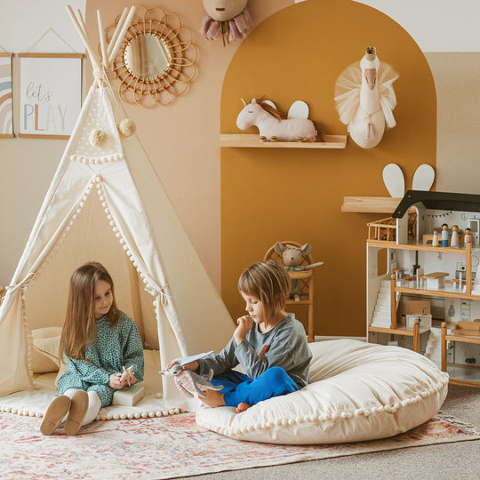 Children playing in a playroom with a teepee, shelves, and toys.