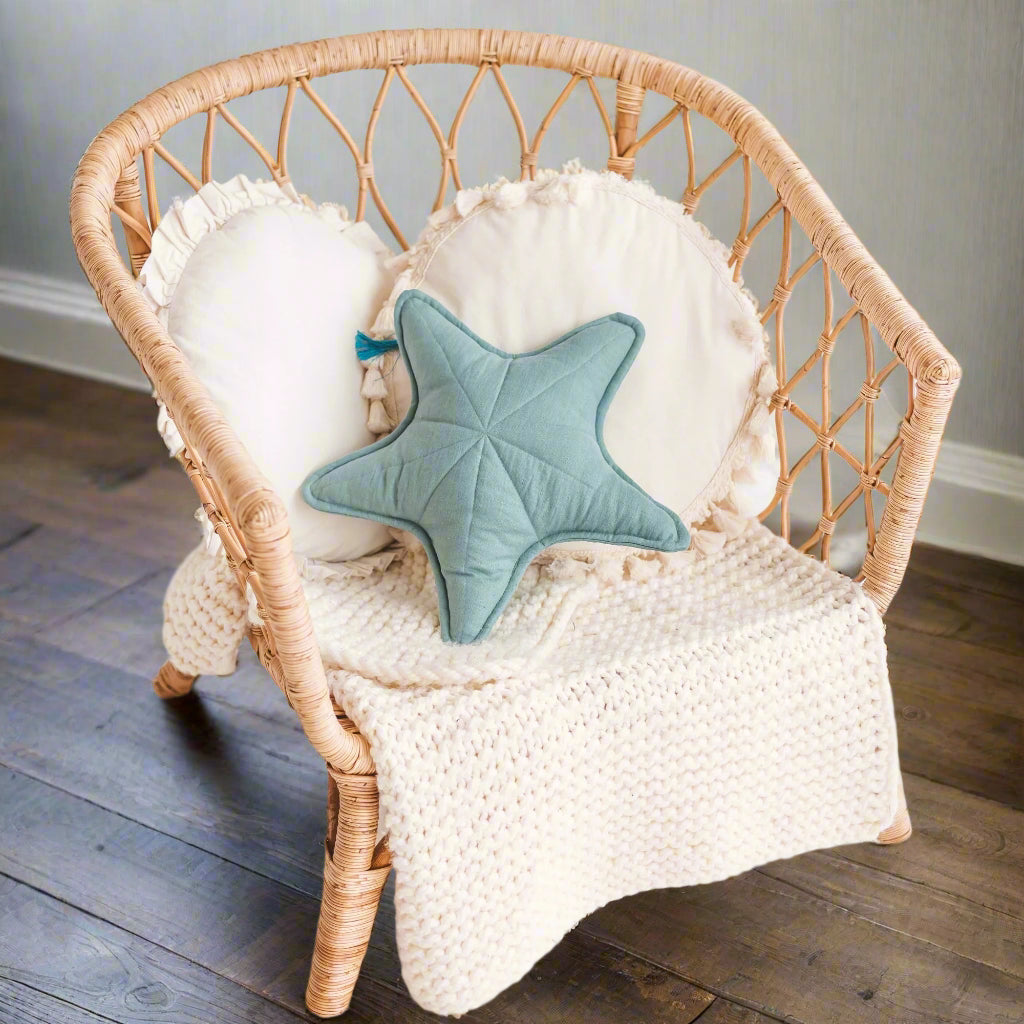 Wicker chair with a blue star-shaped pillow and white blanket