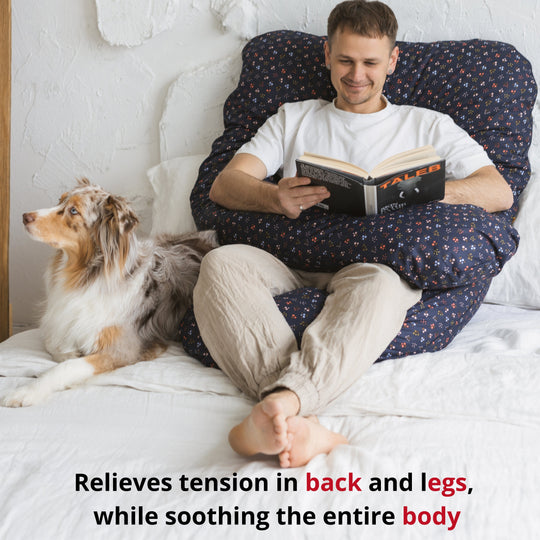 Man reading a book on a bed with a dog beside him, promoting relaxation.