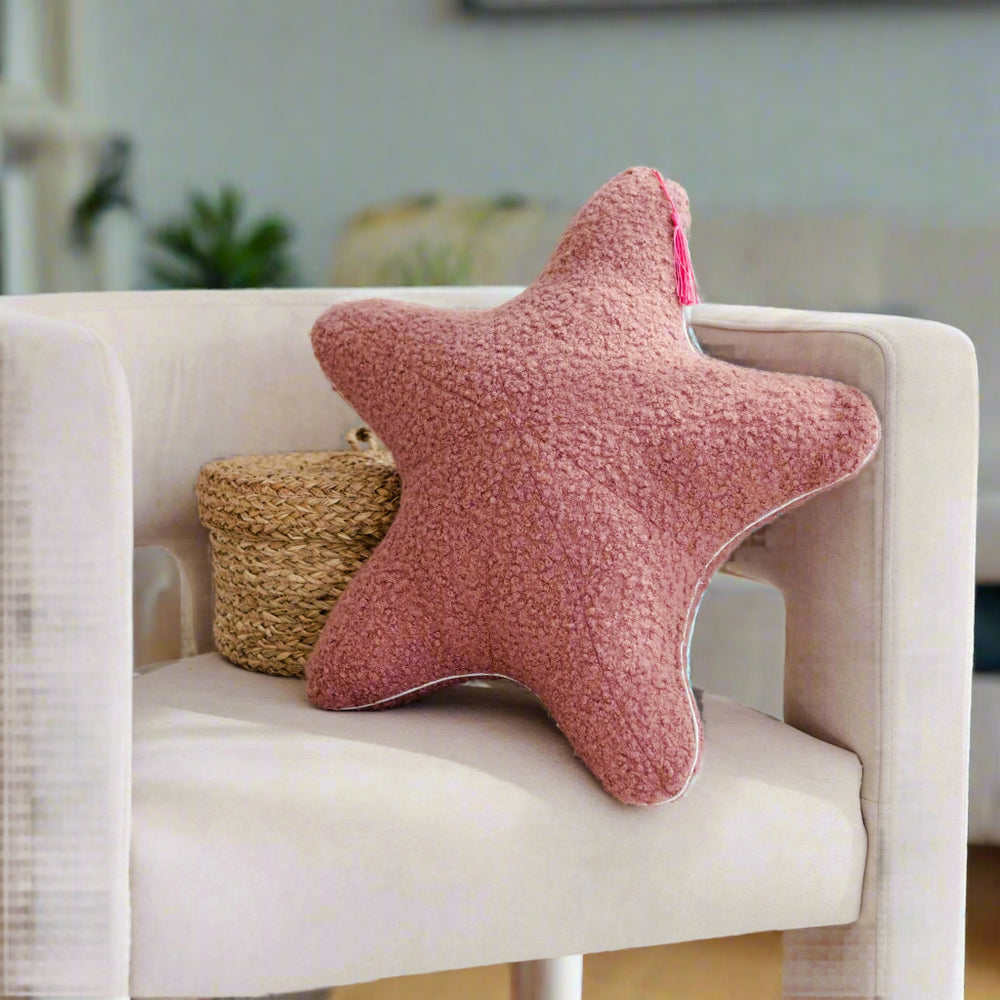 Pink star-shaped pillow on a white chair with a woven basket in the background