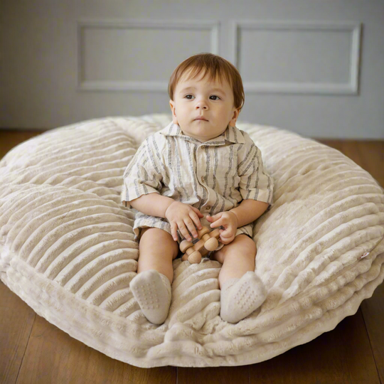 Young child sitting on corduroy floor cushion