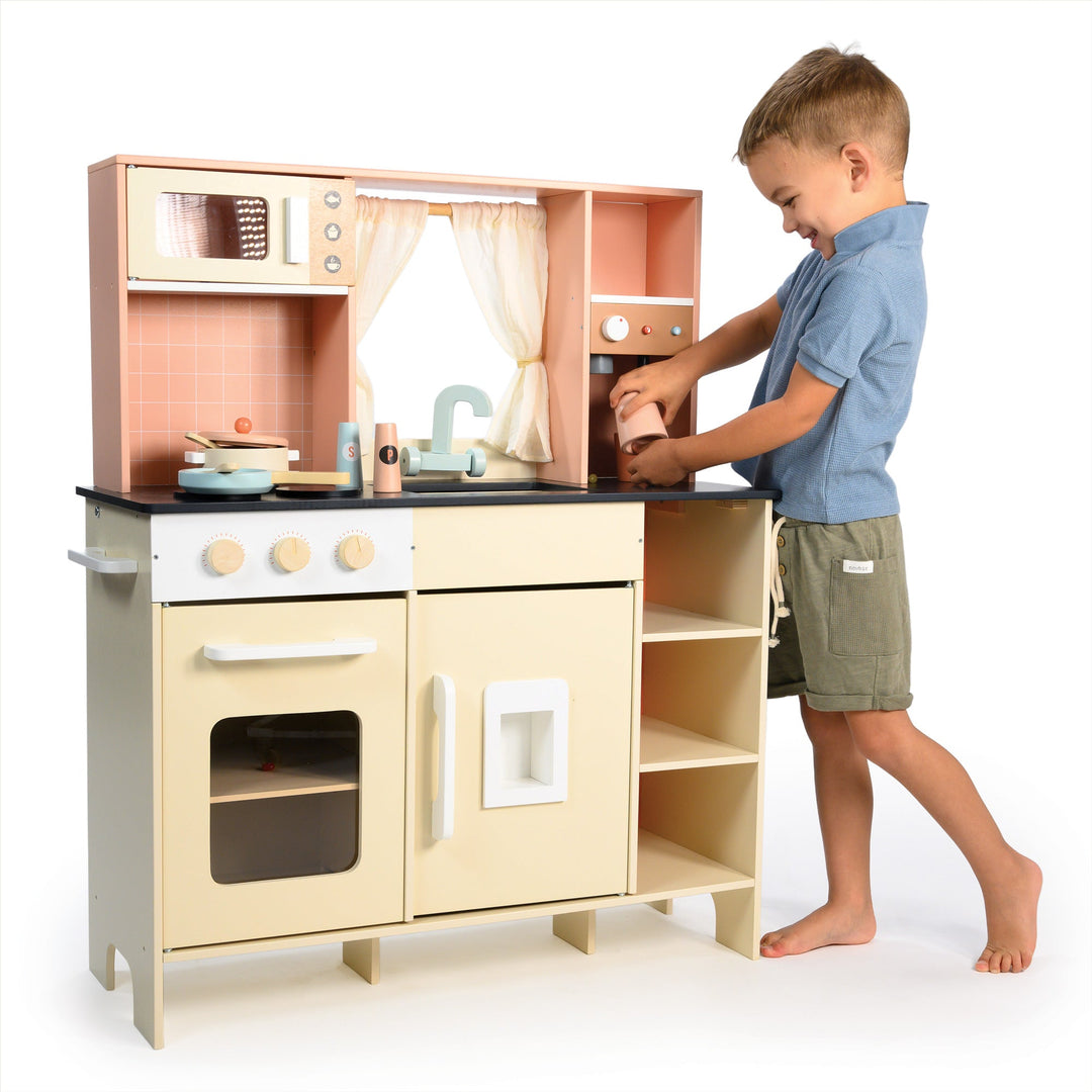 Child playing with a toy kitchen set on a white background