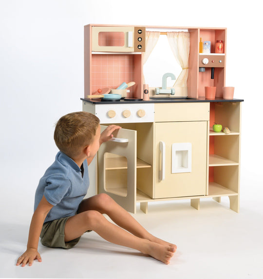 Child playing with a wooden toy kitchen set on a white background