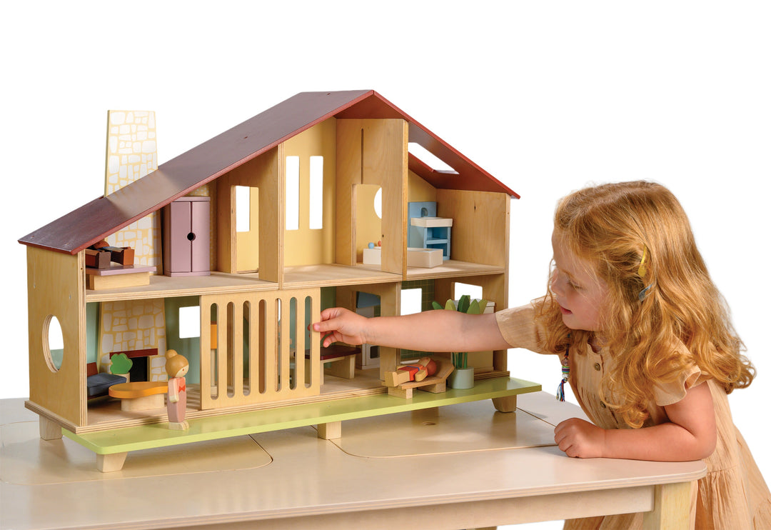 Child playing with a wooden dollhouse on a white background