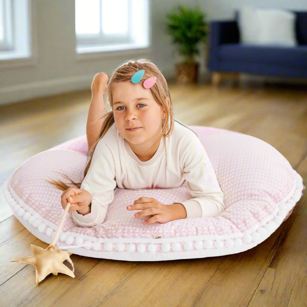 Young girl lying on pale pink large round floor cushion