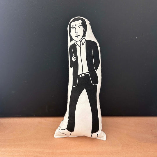 Screen printed cushion doll with white fabric and black illustration depicting musician Nick Cave wearing a black suit and white shirt with the collar unbuttoned