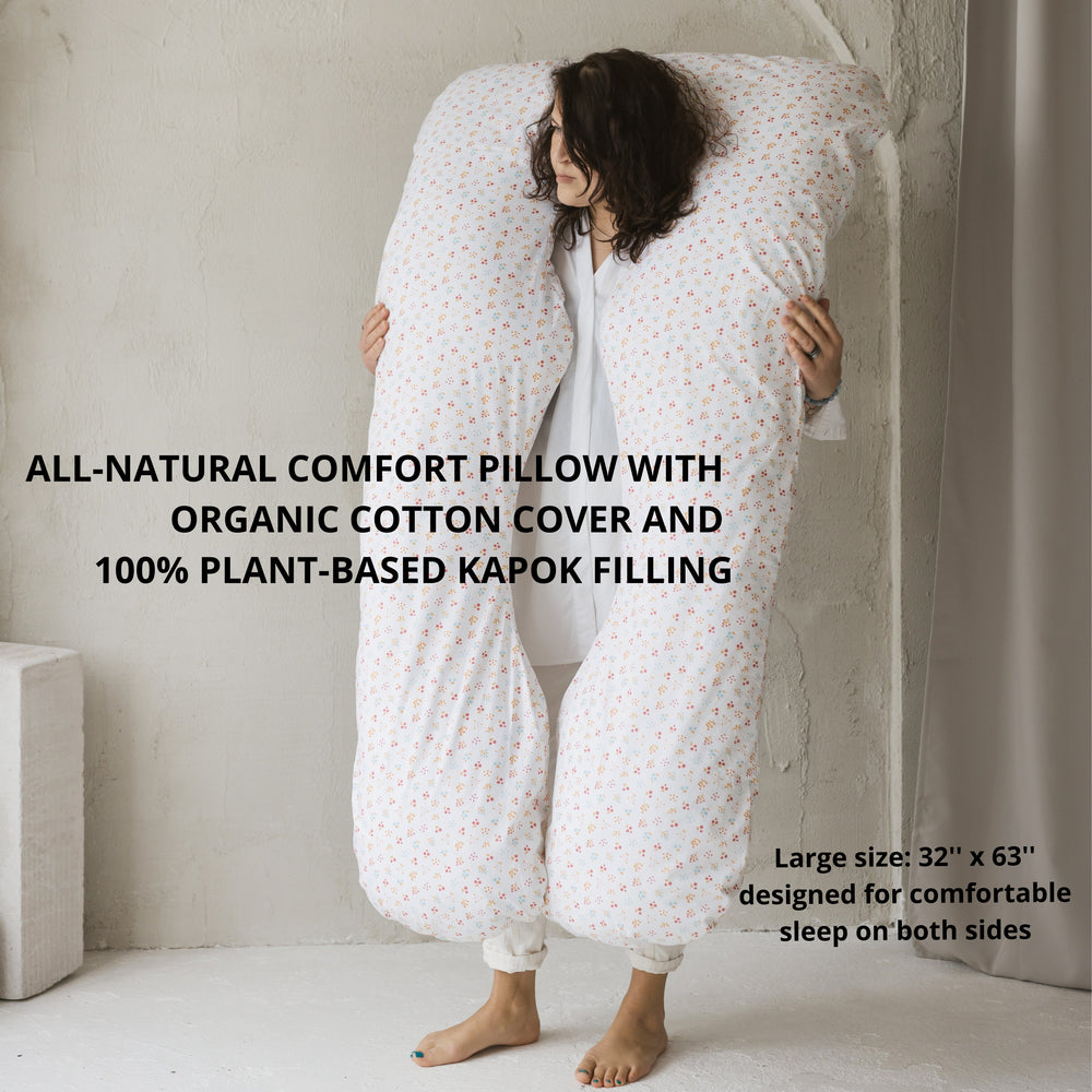 Person holding a large all-natural comfort pillow with organic cotton cover and plant-based kapok filling.