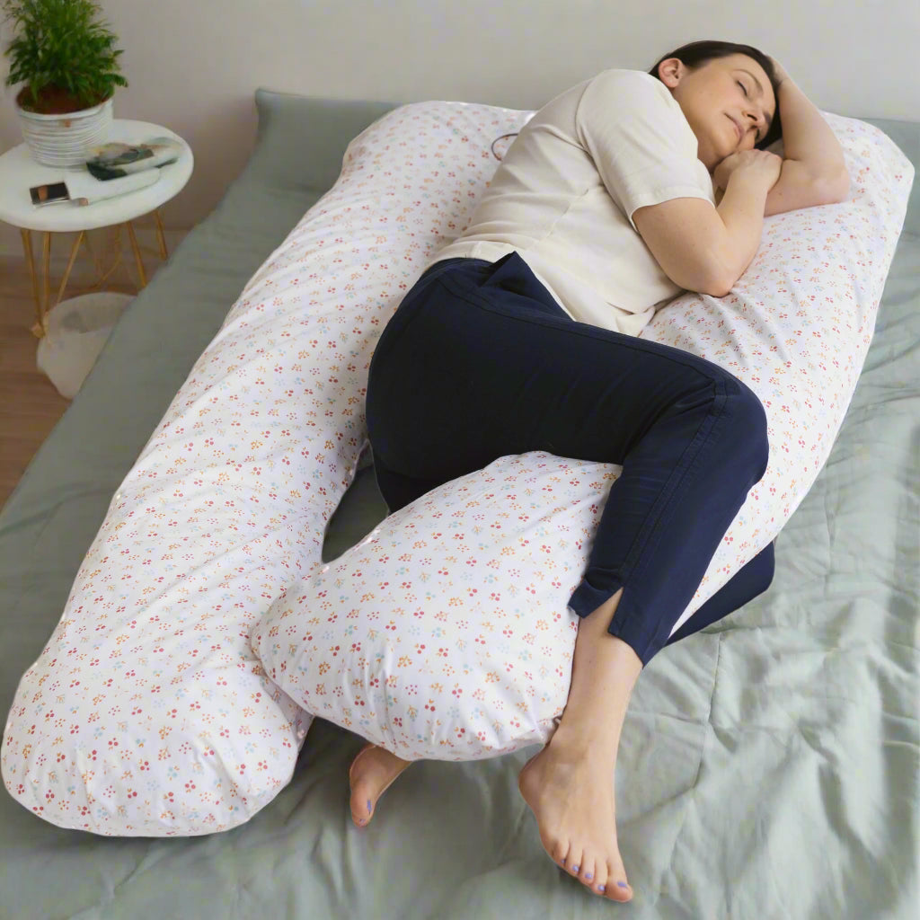 Person lying on a large U-shaped pillow with a floral pattern