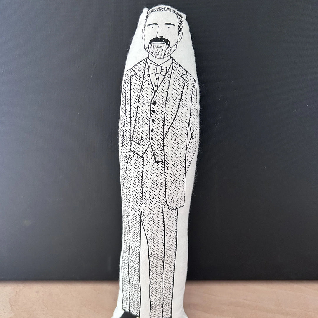 Screen printed doll cushion with white fabric and black illustration depicting Patrick Grant from the Great British Sewing Bee wearing a three-piece tweed suit and bow tie
