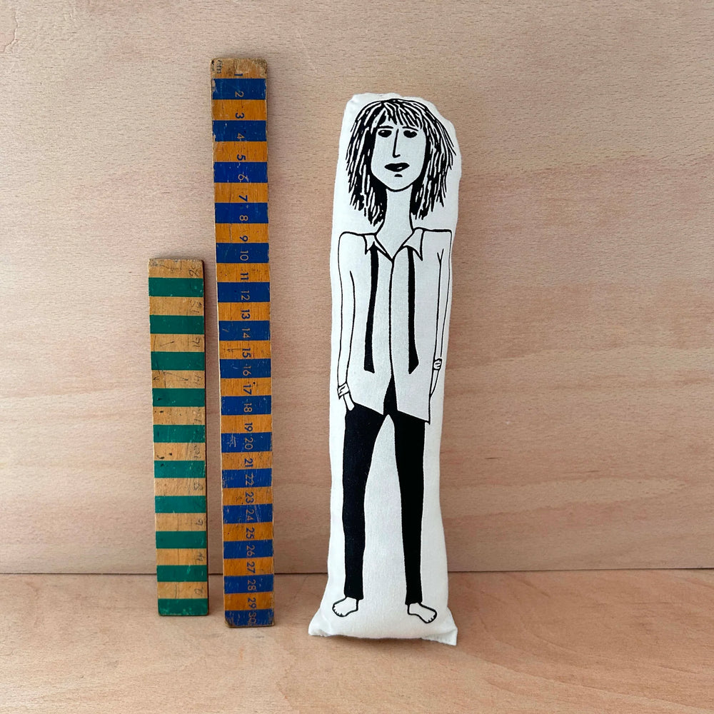Screen printed doll cushion of Patti Smith next to two wooden rulers on a wooden background