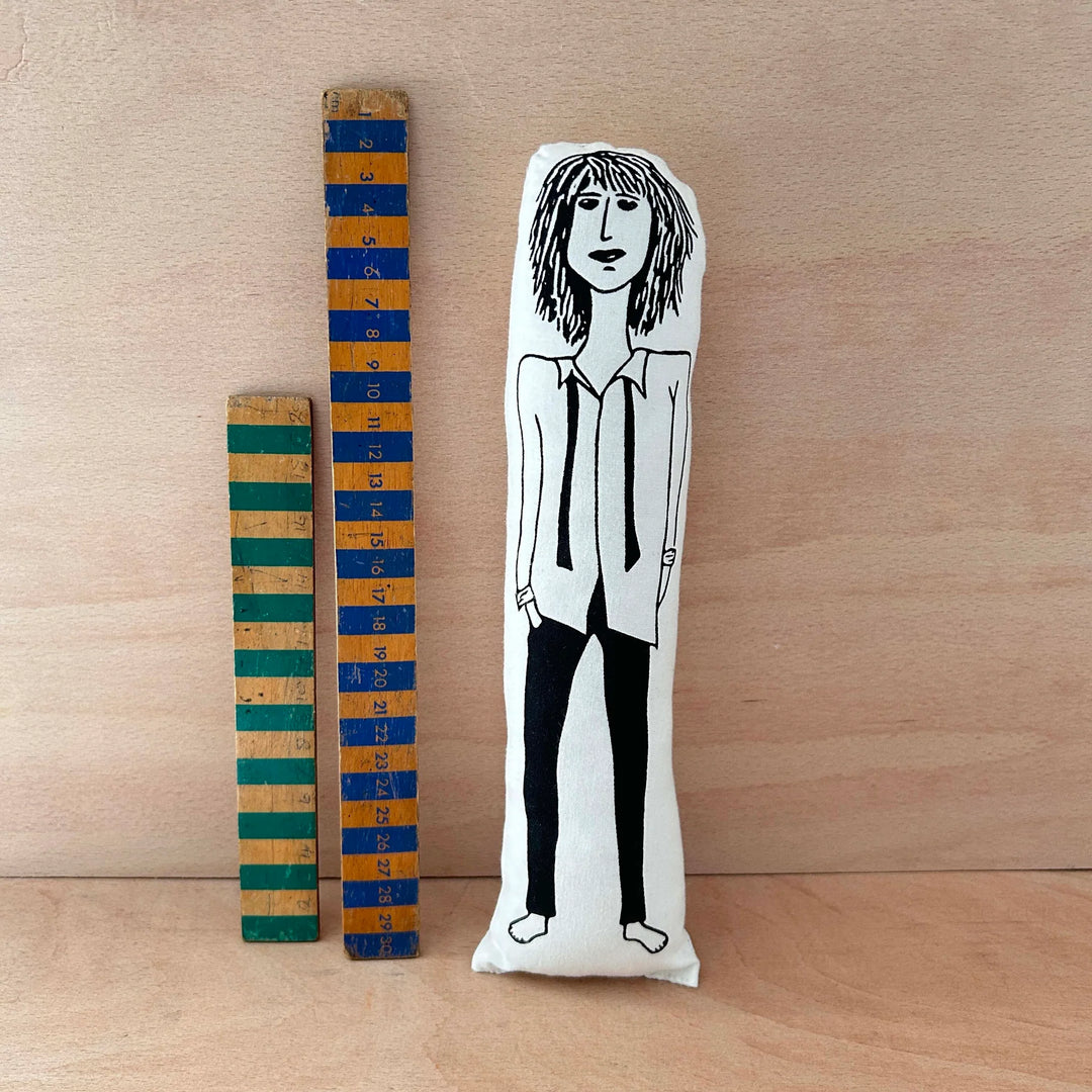 Screen printed doll cushion of Patti Smith next to two wooden rulers on a wooden background