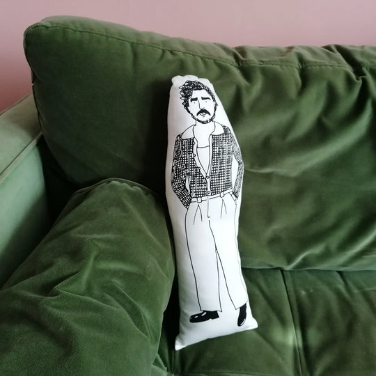 The larger screen printed doll cushion on a green velvet sofa