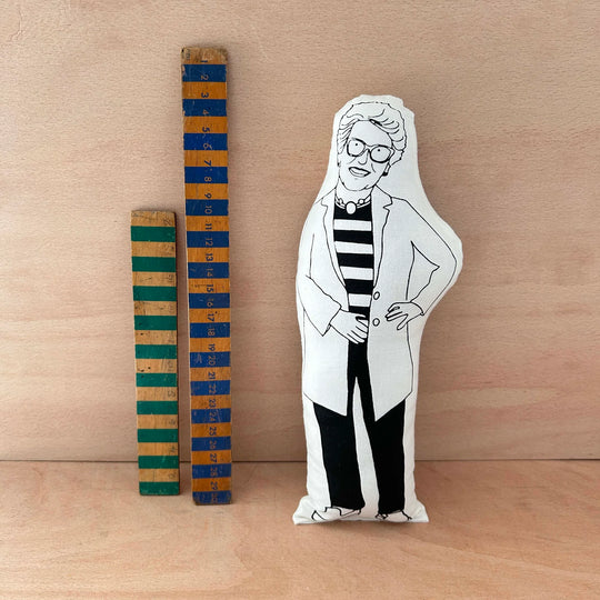 Screen printed doll cushion of Prue Leith next to two wooden rulers on a wooden background