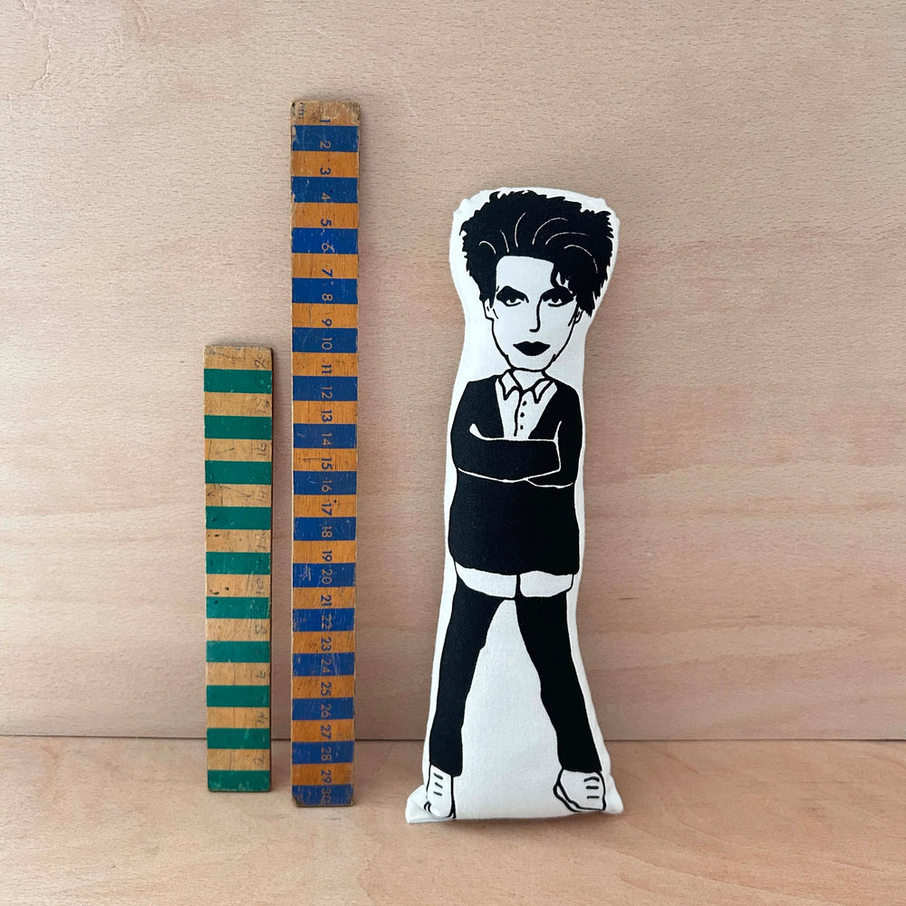 Screen printed black and white doll of Robert Smith next to two wooden rulers