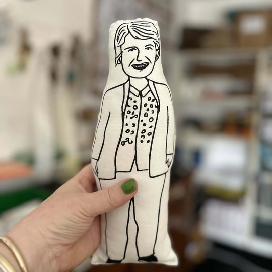 Hand holding screen printed doll of Sandi Toksvig with blurred background