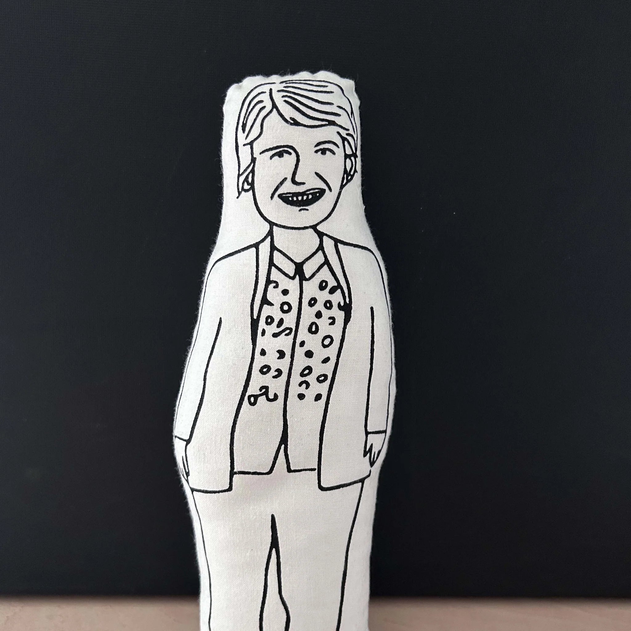 Screen printed black and white doll cushion depicting Sandi Toksvig against a dark background