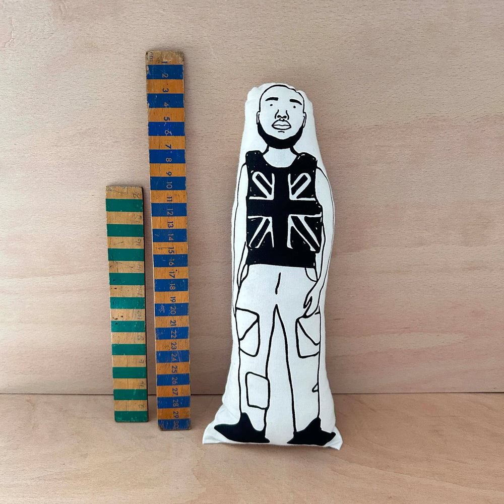 Screen printed black and white doll of Stormzy next to two wooden rulers